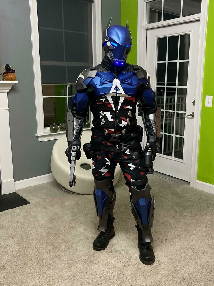A person in a full, intricate 3D printing costume of Arkham Knight, holding two prop guns, demonstrating amazing creations.