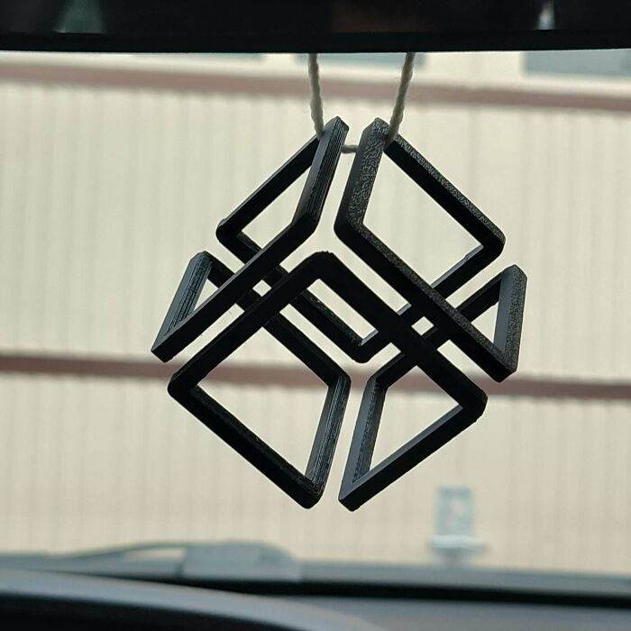 A black, geometrically abstract 3D printing creation hanging as a car ornament, an amazing creation.