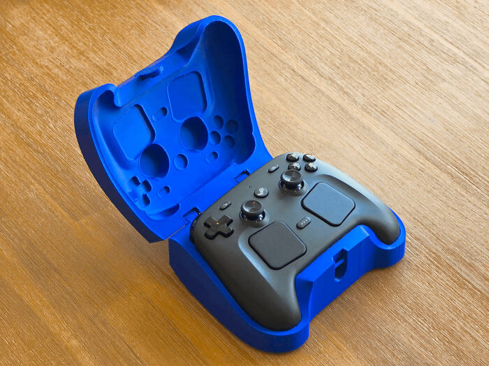 A blue 3D printing case designed to perfectly fit a black video game controller, an amazing creation.