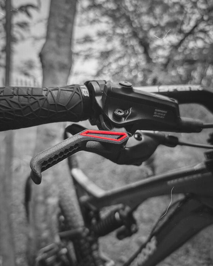 Amazing 3D printing creation: a custom brake lever with a red highlight on a mountain bike in grayscale.