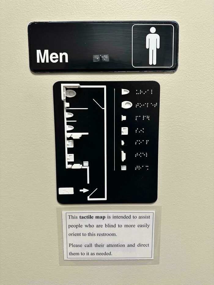 A black sign for a men's restroom with a tactile map and Braille, an amazing creation for the visually impaired.