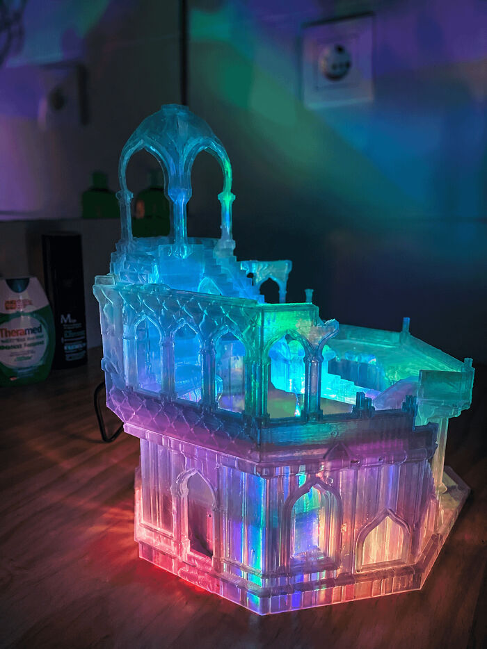 A glowing, colorful 3D printing creation resembling an ornate building, showcasing amazing creations by fans.
