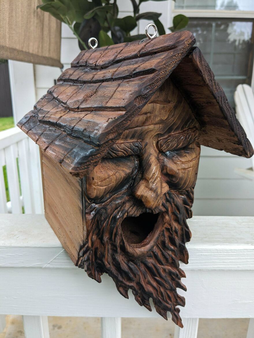 A wooden birdhouse carved into a man's face with a beard, a unique piece of whimsical crafts.