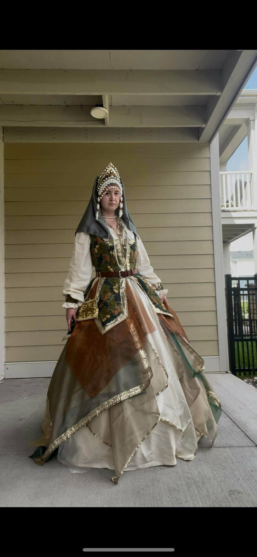 A person in a whimsical, magical, elaborate dress and ornate headpiece, showcasing a stunning craft costume.