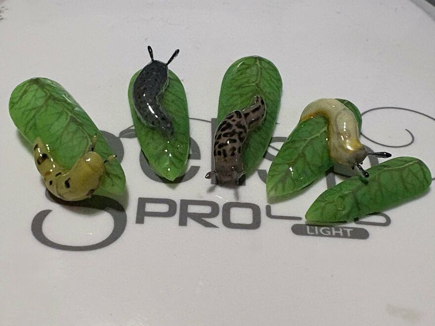 Five whimsical crafts of slugs on green leaves, showcasing magical and shared online art.