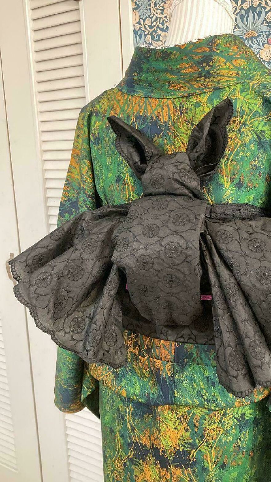 Whimsical crafts: A person wearing a green and orange garment with a black bat-shaped bow tie, a truly magical outfit.