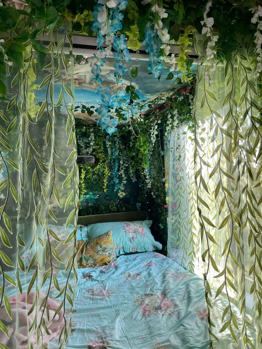A whimsical crafts bedroom with a canopy of green and blue artificial vines, surrounding a bed with floral sheets.