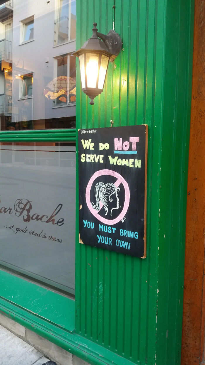 A sign outside a bar that says WE DO NOT SERVE WOMEN. YOU MUST BRING YOUR OWN. Funny memes for health.