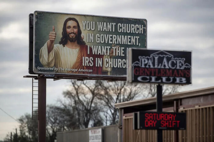 A funny meme billboard showing Jesus giving a thumbs up, paired with a sign for a gentleman's club.