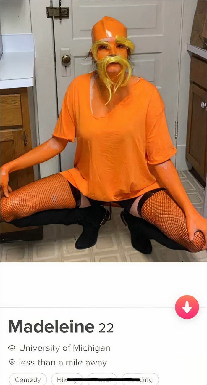 A woman in a Lorax costume, crouching, with orange body paint and a yellow mustache, a cringe Tinder profile.