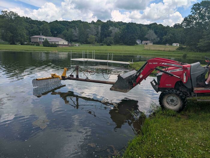 A tractor with a rake attachment, cleaning a pond, an example of people turning random junk into clever solutions.
