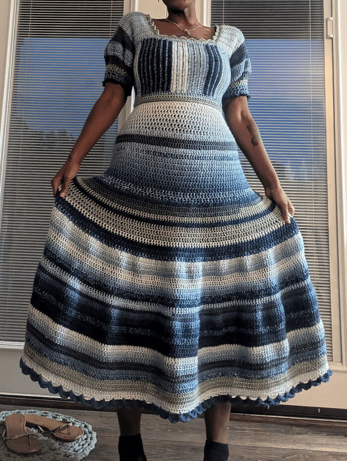 A person standing in a floor-length blue and white striped crochet dress, a beautiful DIY creation.