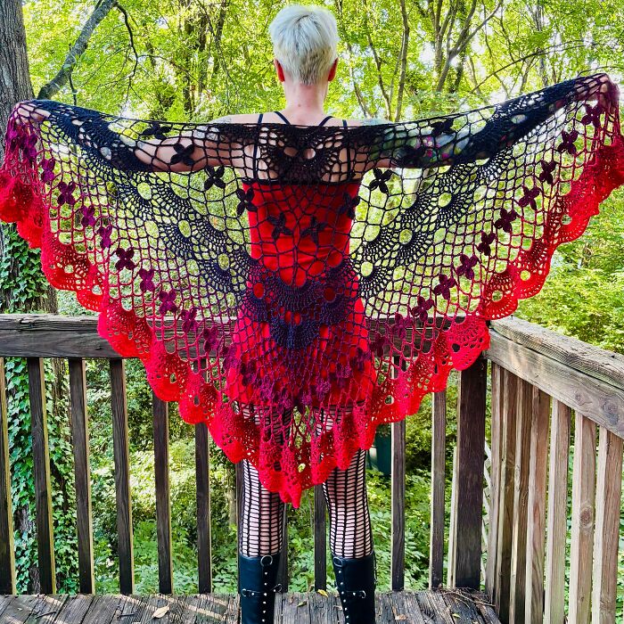 A woman wearing a beautiful red and black crochet shawl, showcasing a useful DIY creation.