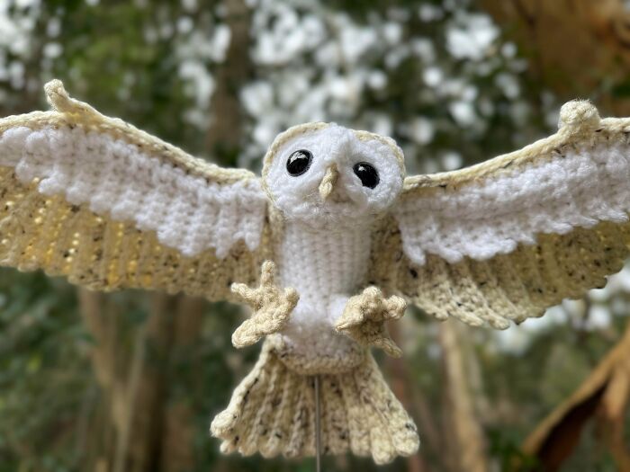 A close-up of a white and beige DIY crochet owl with outstretched wings, a useful crochet creation.
