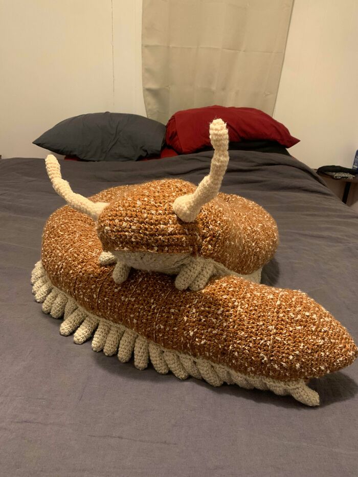 Two large crochet snails, a mother and baby, resting on a bed as useful DIY creations.