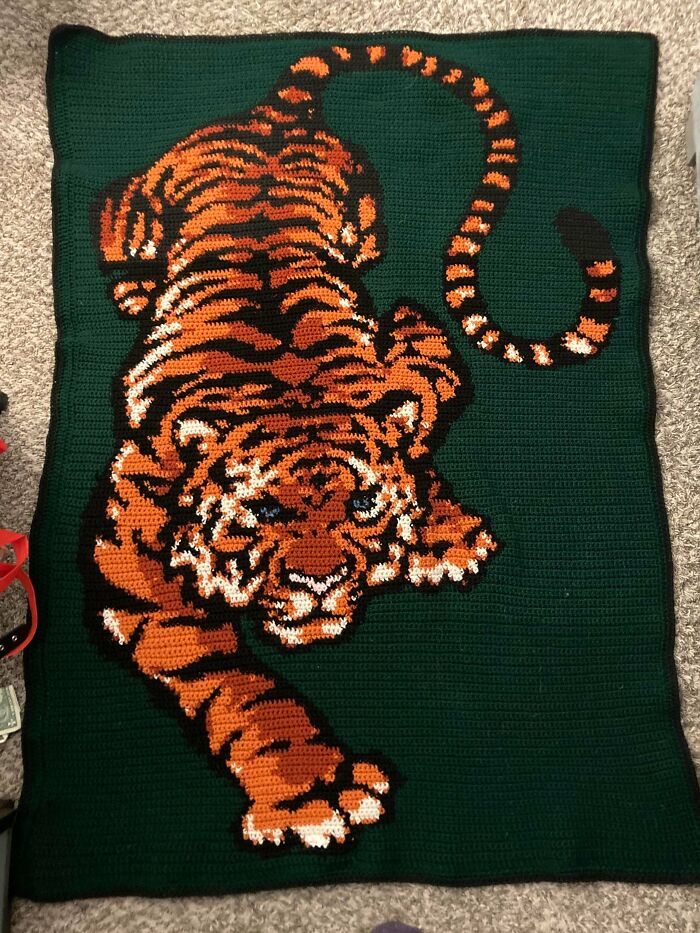 A DIY crochet blanket with a large, detailed tiger design in orange and black on a green background.
