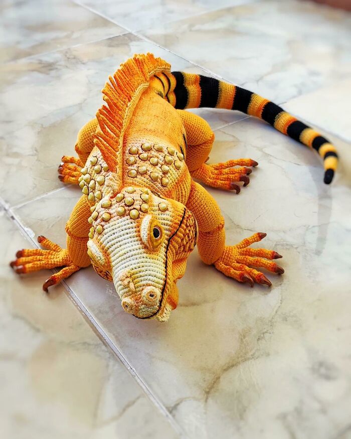 A detailed orange crochet iguana with a striped tail, a very useful DIY creation.