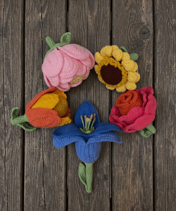A collection of five colorful crochet flowers, including a pink peony, yellow sunflower, orange tulip, red rose, and blue iris, useful DIY creations.