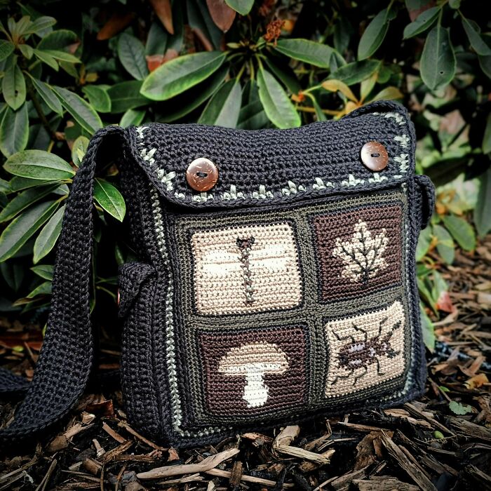 A black crochet bag featuring unique nature-themed square patterns like a dragonfly and a mushroom, a useful DIY creation.