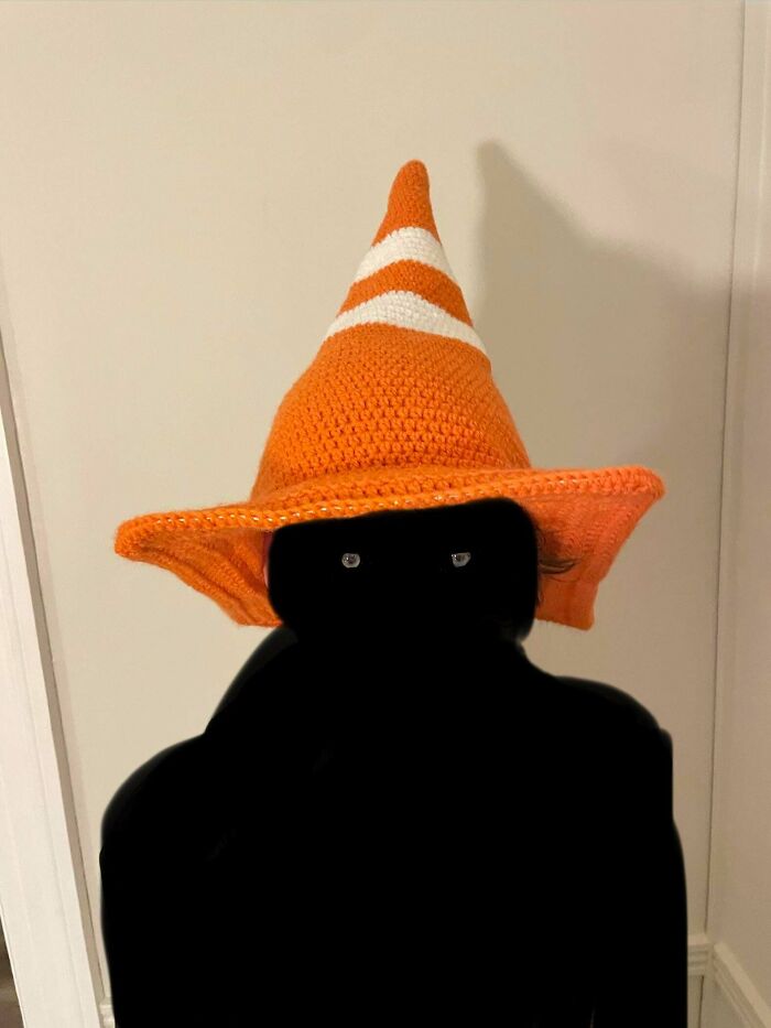 A person wearing a traffic cone crochet hat, a fun example of useful DIY crochet creations.