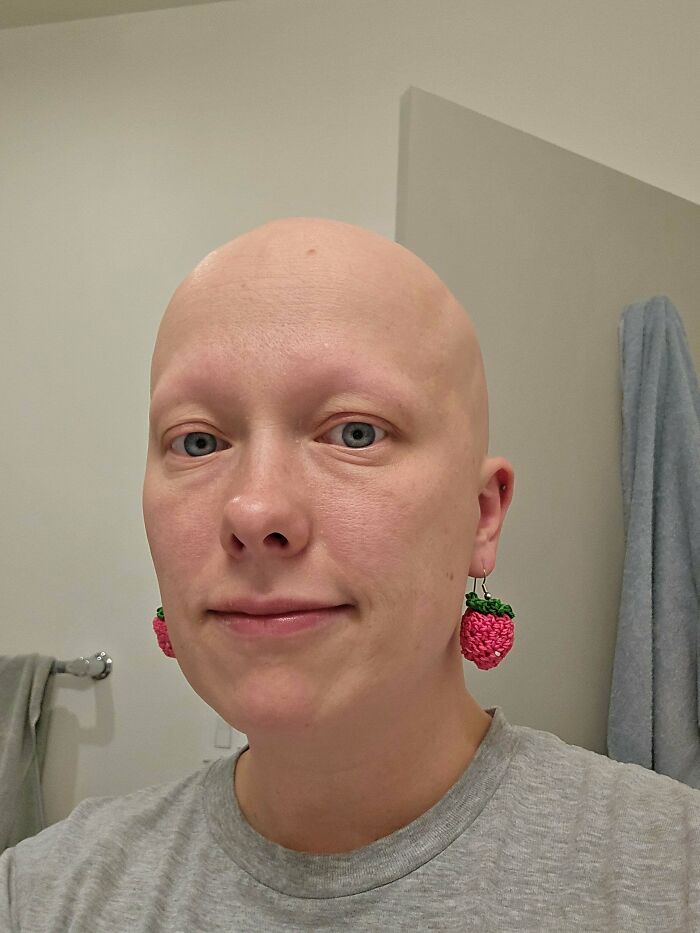 A woman with strawberry crochet earrings, showing off a useful DIY crochet creation.
