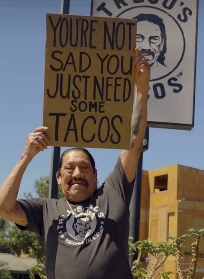 Danny Trejo holding a sign saying You're Not Sad You Just Need Some Tacos, a piece of bad advice.