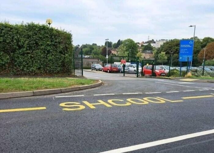 A road painting near a school entrance that misspells school as SHCOOL, illustrating cultural decline.