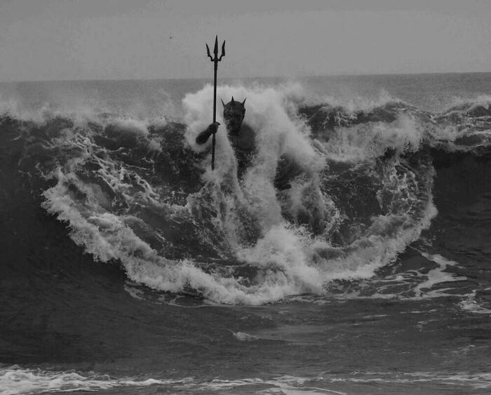 A figure with a trident emerges from a massive wave, creating a creepy image that could be nightmare fuel.