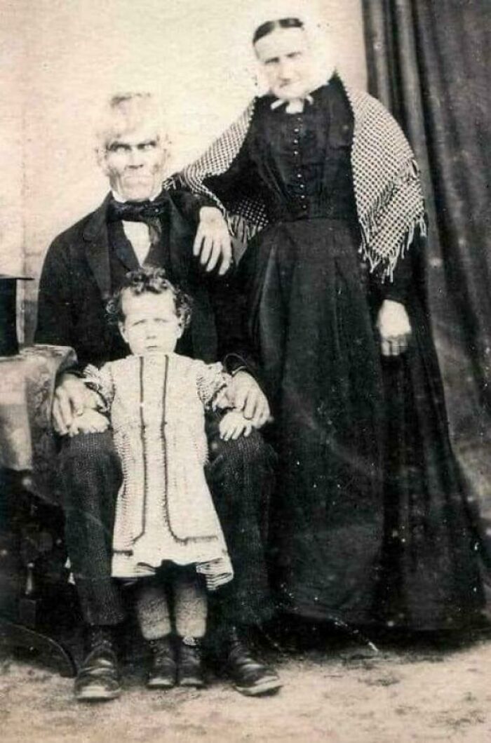 A creepy, sepia-toned vintage photo of a stern-faced family with a young child. A truly unsettling image, nightmare fuel.