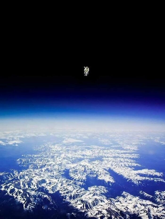 An astronaut floating above Earths snowy mountains, creating a creepy and lonely image.