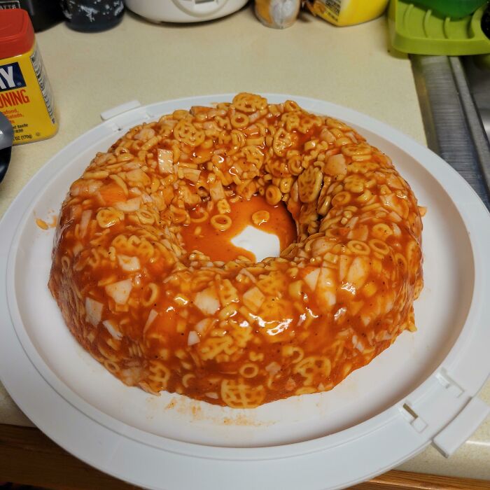 A ring-shaped mold of spaghetti-o's on a white plate, highlighting a presentation of disgusting food.