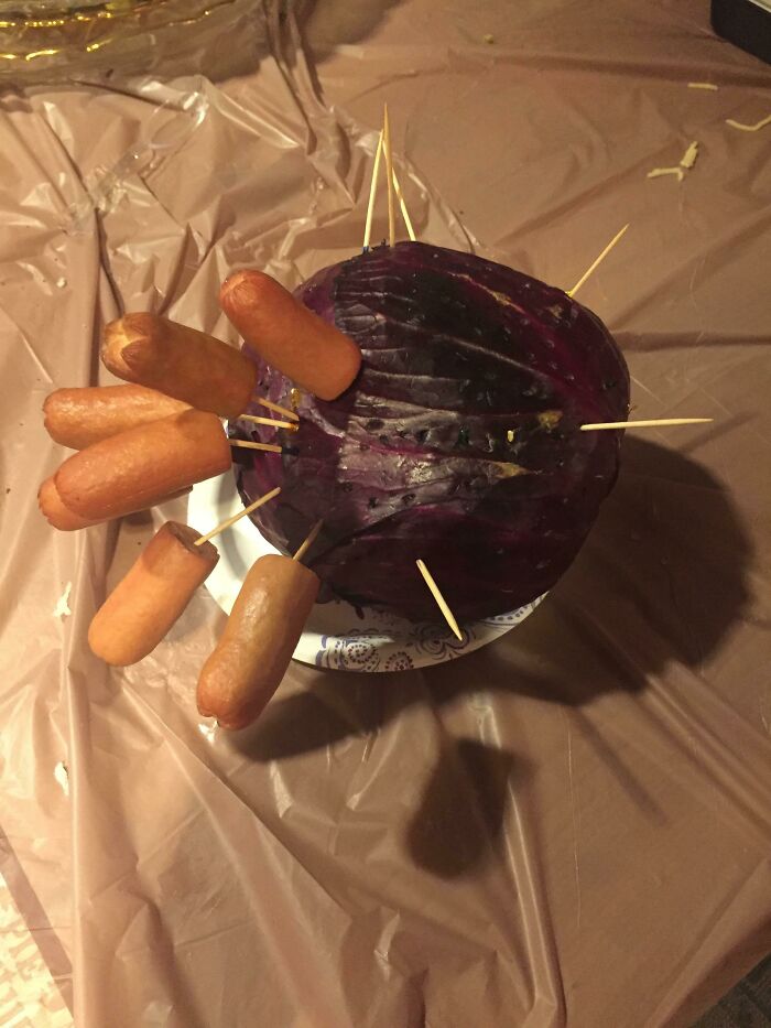Hot dogs skewered into a purple cabbage, a truly disgusting food presentation.