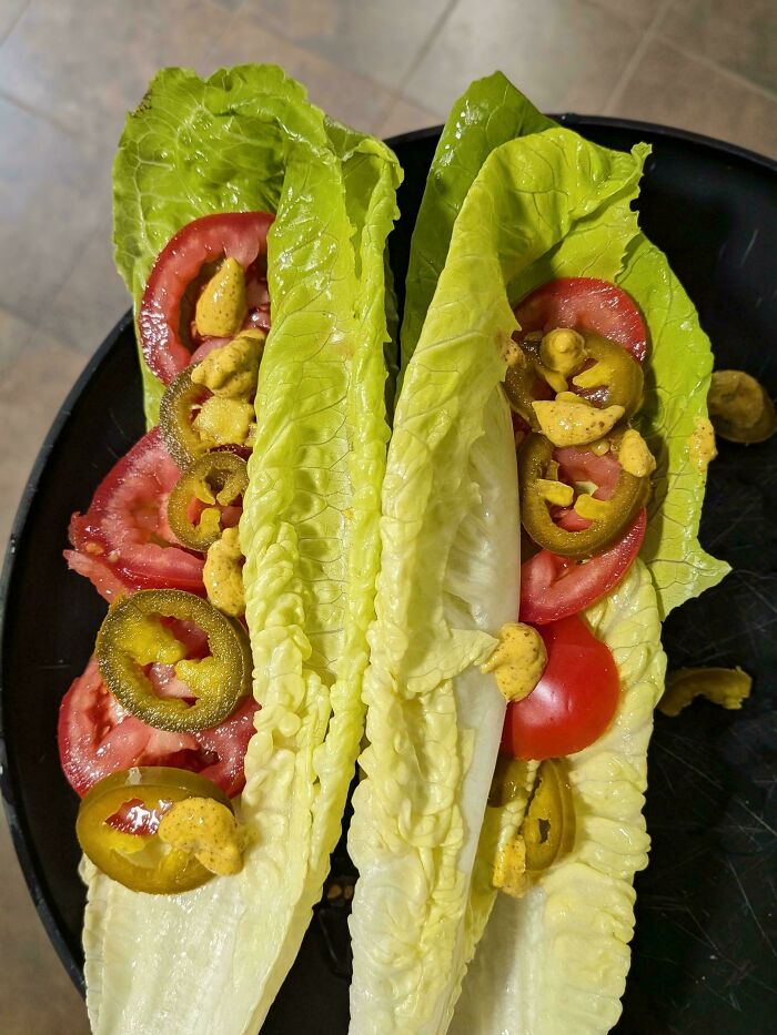 Lettuce wraps with tomatoes, jalapeños, and mustard, appearing as unappetizing, disgusting food.