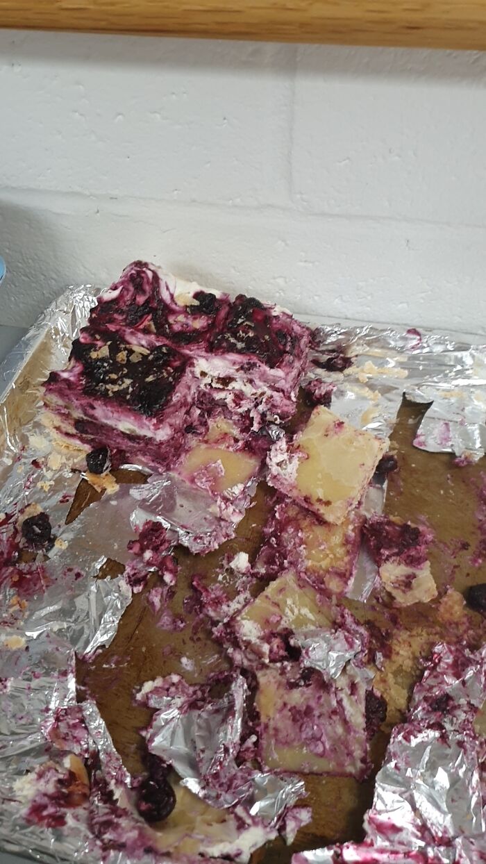 A messy, partially eaten tray of blueberry dessert, resembling disgusting food.