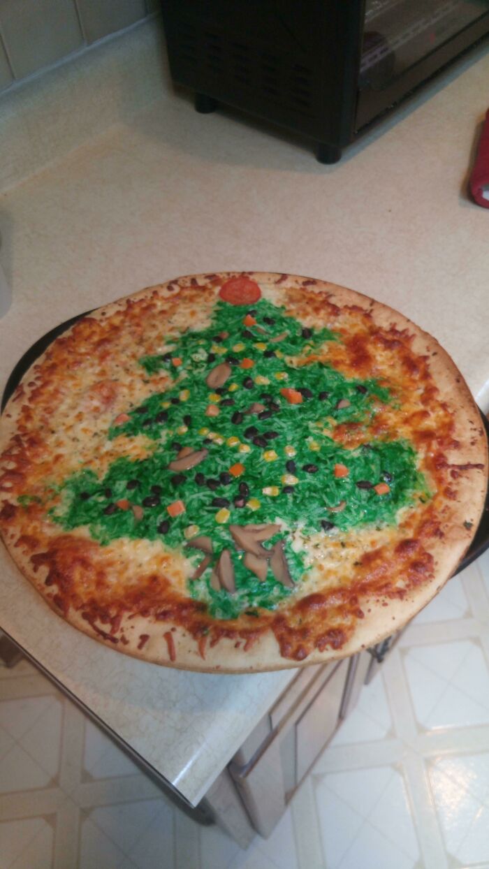 A pizza decorated with green topping and various vegetables to look like a Christmas tree, an example of disgusting food.
