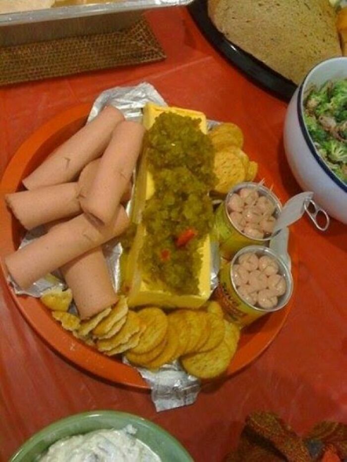A platter with hot dogs, crackers, a block of cheese with relish, and canned beans, an example of disgusting food.