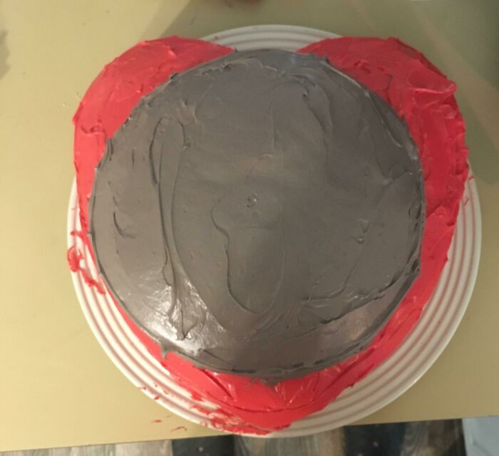 A heart-shaped cake covered in gray and red frosting, resembling disgusting food that deserves to be publicly shamed.
