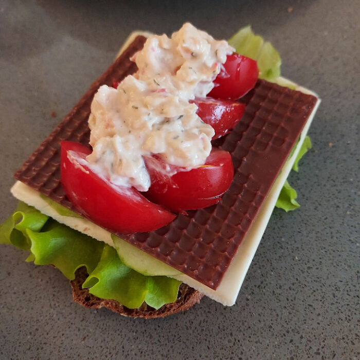 A bizarre, disgusting food combination featuring lettuce, cheese, chocolate, tomatoes, and a creamy topping.
