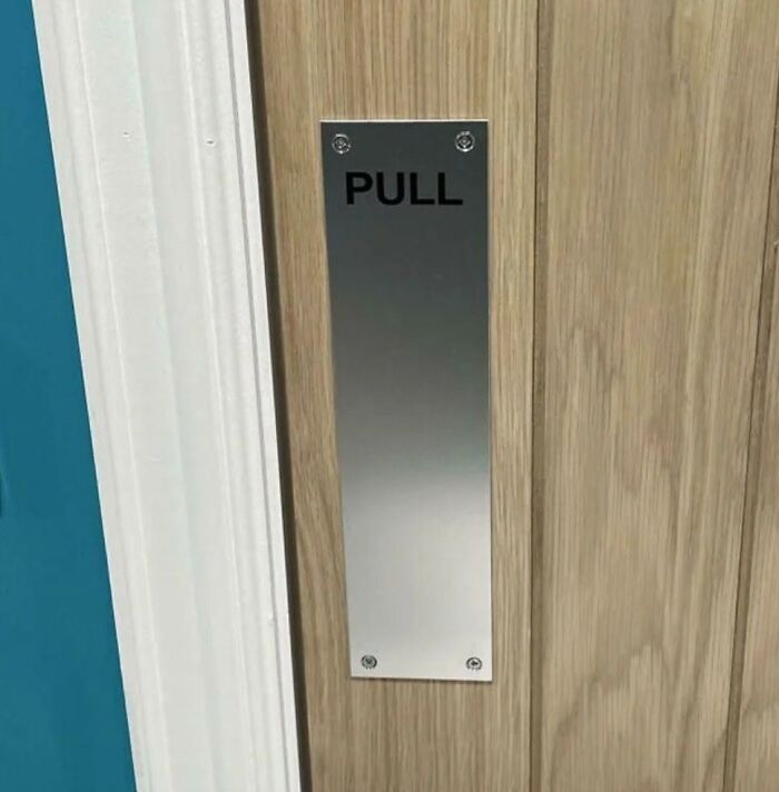 A door with a pull sign on a metal plate, humorously demonstrating cultural decline into idiocy.