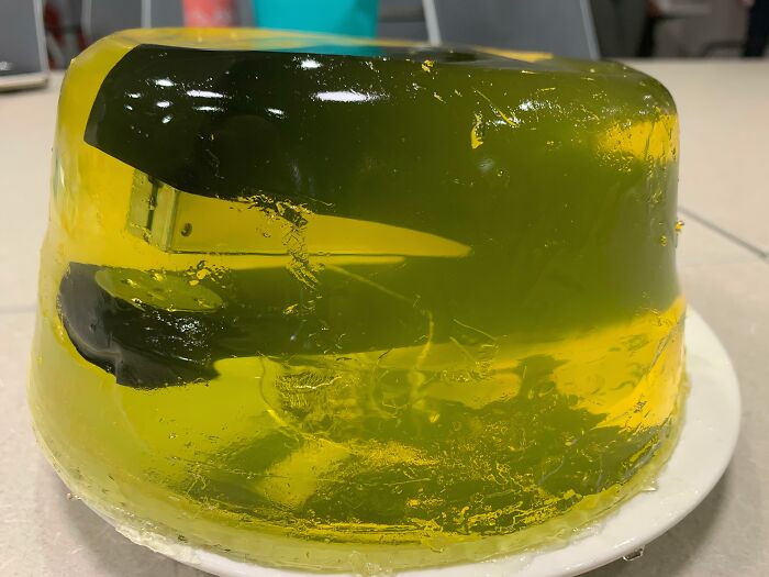 A stapler encased in green jello, a disgusting food prank, not edible.