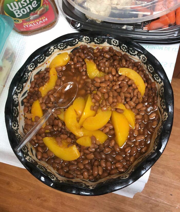 A bowl of brown beans topped with sliced peaches, a creation considered disgusting food.