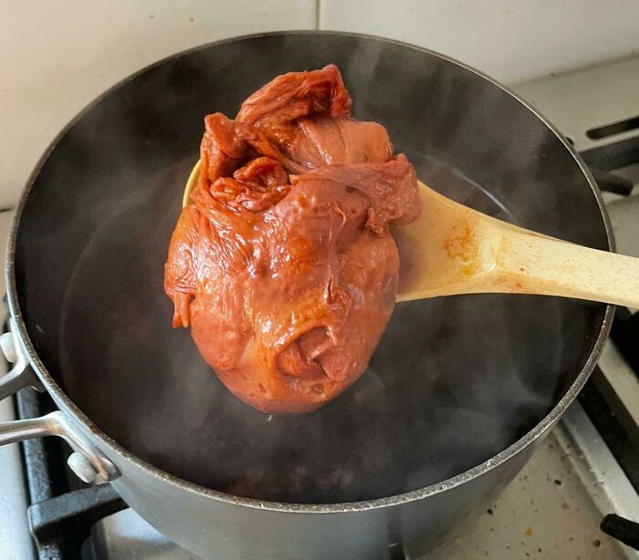 A red, heart-shaped piece of vegan food being boiled in a pot, highlighting stupid vegan food.