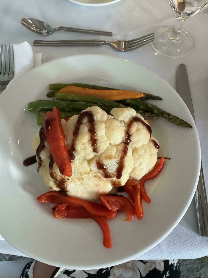 A plate with cauliflower, red peppers, and asparagus drizzled with sauce, representing stupid vegan food.
