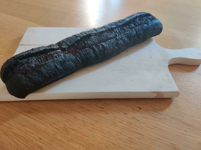 A burnt baguette on a white cutting board, symbolizing stupid vegan food that deserves to be shamed.