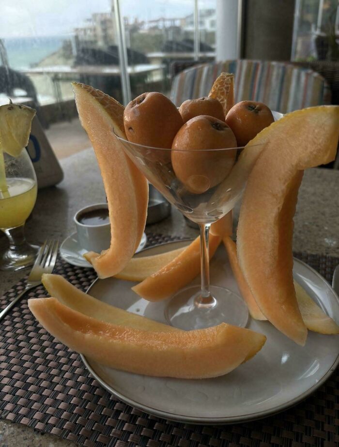 A fancy glass with melon slices and small fruits, illustrating stupid vegan food that deserves to be shamed.