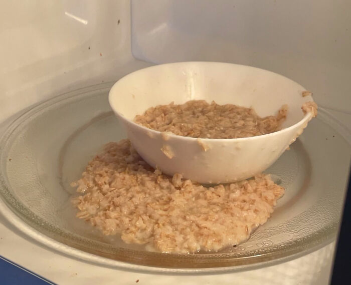 Overcooked oatmeal spilled from a bowl in a microwave, depicting stupid vegan food that deserves to be shamed.