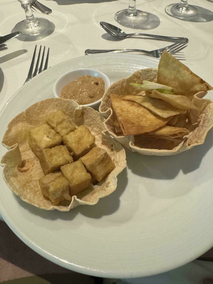 Fried tofu cubes and tortilla chips in edible bowls with dipping sauce, as stupid vegan food that deserves to be shamed.