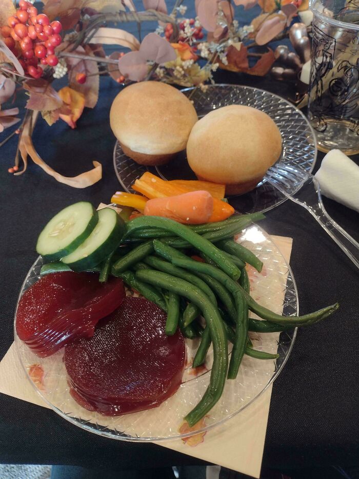A plate with rolls, green beans, carrots, cucumber, and cranberry jelly, a sad example of stupid vegan food.