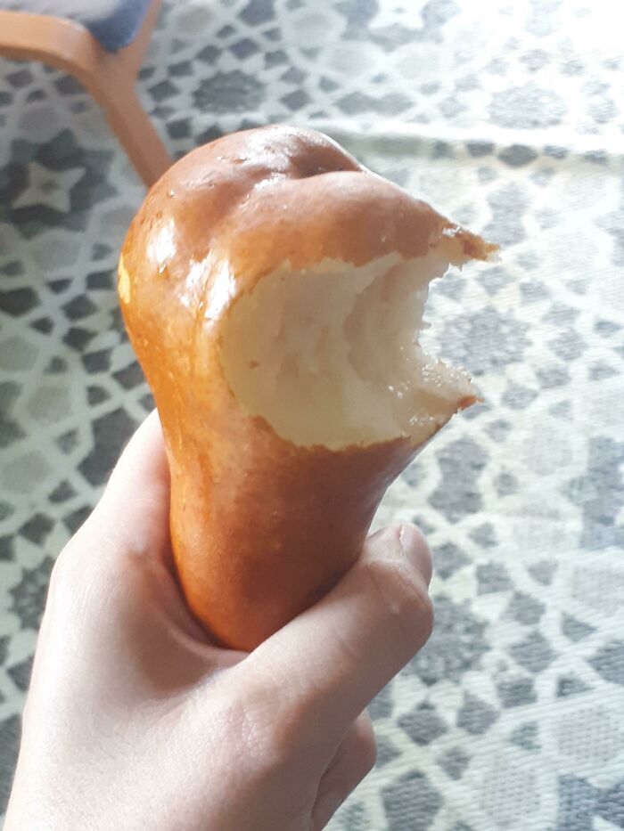 Stupid vegan food: A person holds a pear with a large bite taken out of its side, revealing the white flesh.