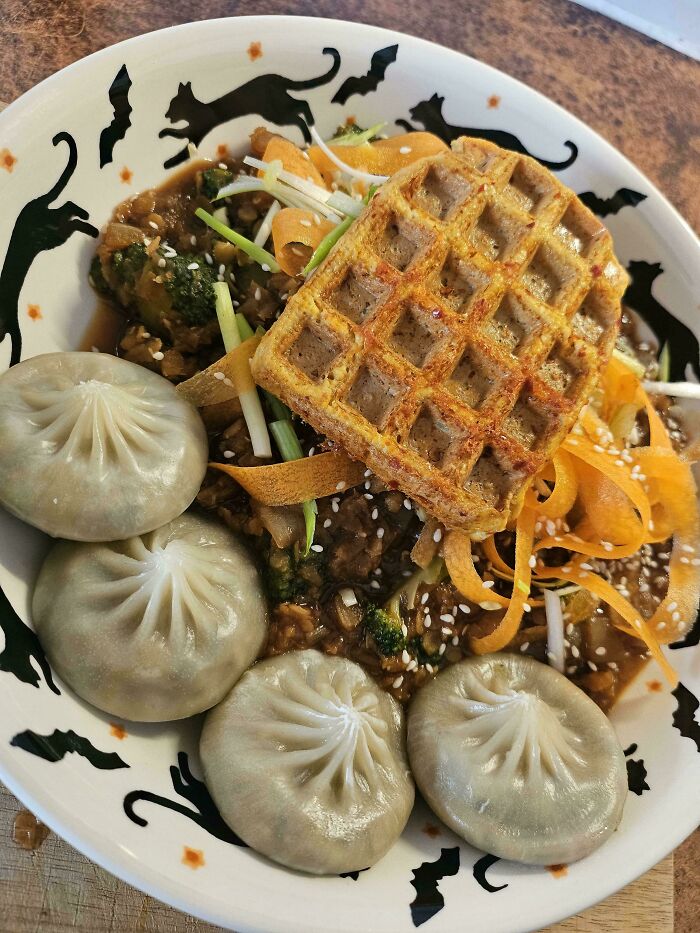 A bowl of vegan food, featuring dumplings, a waffle, and vegetables, potentially deserving public shaming for its odd combination.